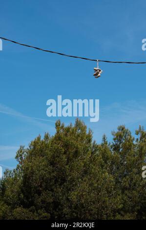 Sneakers appesi alle linee elettriche. Lanciarsi con la scarpa. Divertimento o marcatura del territorio. Foto Stock