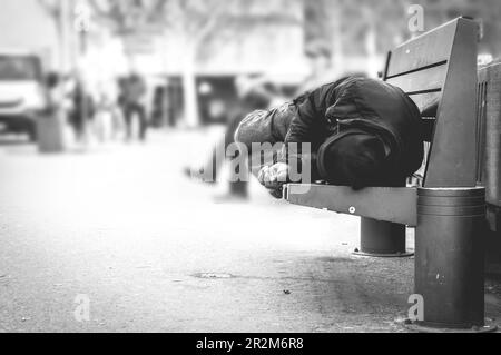 Povero stanco depresso affamato uomo senza casa o rifugiato che dorme sulla panchina di legno sulla strada urbana in città, concetto di documentario sociale Foto Stock