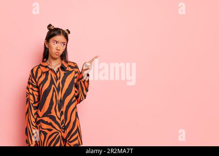Thailandese dispiaciuta ragazza vestita in sovra dimensione zebra design camicia indica spazio vuoto per la vostra pubblicità, copia spazio, shopping tempo concetto Foto Stock
