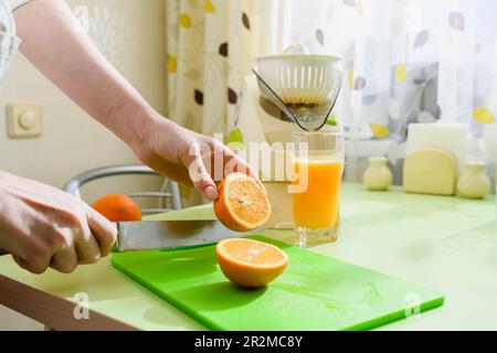 Cibo sano a casa. La donna sta preparando il succo d'arancia fresco in cucina. Foto Stock