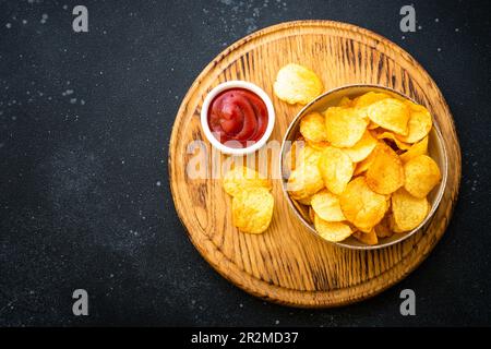 Patatine e ketchup su tavolo nero. Vista dall'alto. Foto Stock