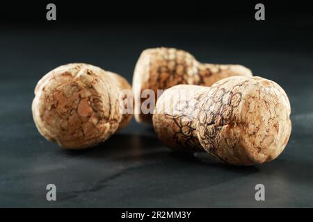 Tappi di bottiglie di vino con immagini d'uva su tavola nera, primo piano Foto Stock