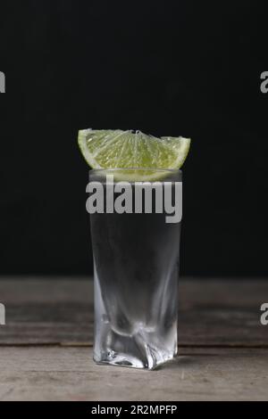 Colpo di vodka con fettina di lime su tavolo di legno Foto Stock