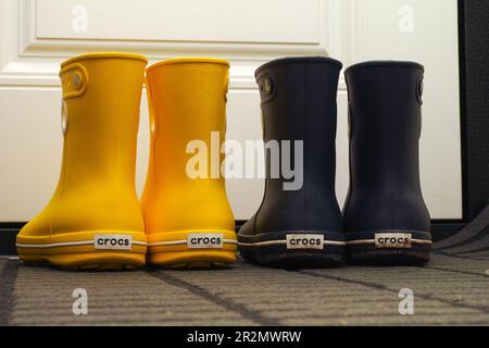Tambov, Federazione Russa - 08 agosto 2019 due paia di stivali in gomma Crocs in piedi in un corridoio vicino ad una porta bianca. Foto Stock
