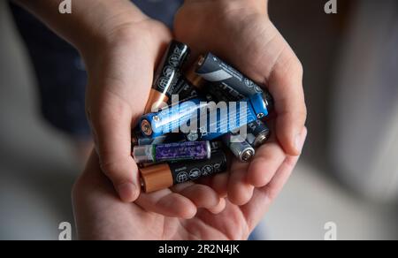 Concetto di riciclaggio ecologico, poche batterie usate in mano. Foto Stock