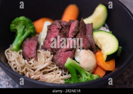 Bistecca di manzo alla griglia e minestra di verdure estive in stile asiatico di Ramen noodle. Foto Stock