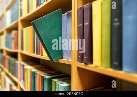 Libro verde esteso da libri colorati sugli scaffali in biblioteca pubblica Foto Stock