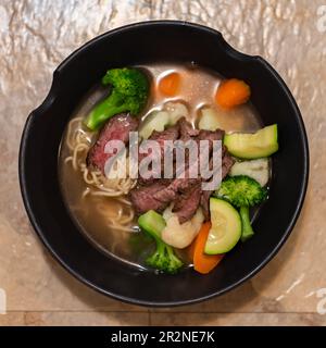 Bistecca di manzo alla griglia e minestra di verdure estive in stile asiatico di Ramen noodle. Foto Stock