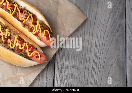 Hot dog grigliato con senape gialla e ketchup su tavolo di legno Foto Stock