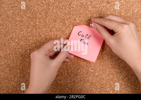 Donna pinning carta nota con frase Chiama mamma per sughero bordo, primo piano Foto Stock