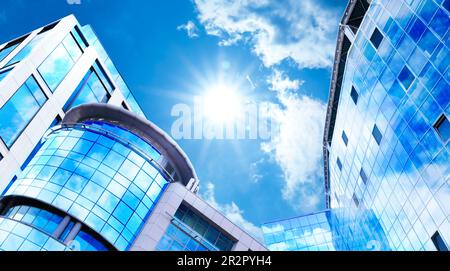 Bel cielo blu con nuvole che si riflettono nelle finestre. Vista ad angolo basso degli edifici moderni nelle giornate di sole Foto Stock