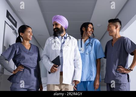 Felice diversi medici maschili e femminili sorridenti l'un l'altro in corridoio all'ospedale Foto Stock