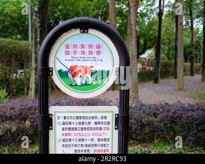 Segno bilingue in inglese e cinese chiedendo ai proprietari di guinzaglio e ripulire dopo il loro cane; Daan Park Taipei, Taiwan; scoop esso in su, mantenga esso leashed. Foto Stock