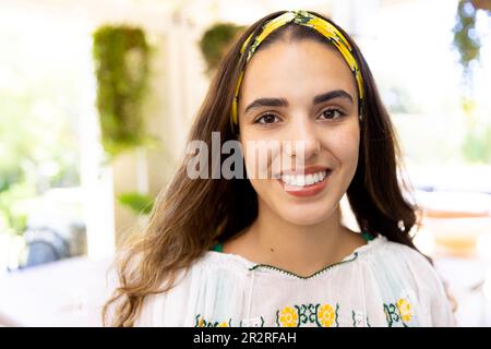 Primo piano ritratto di sorridente giovane donna biraciale indossando fascia gialla a casa, copia spazio Foto Stock