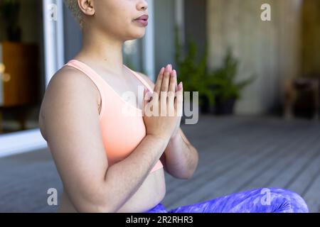 A metà della tranquilla donna biraciale inalterata pratica yoga meditazione seduta sul ponte. Relax, benessere e stile di vita sano. Foto Stock
