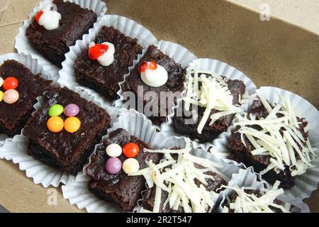 Brownie al cioccolato in una scatola con vari condimenti Foto Stock
