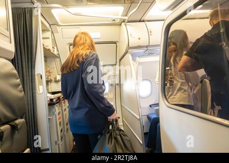 Passeggeri a bordo di un aereo Airbus A320 gestito da Fly Arna. vista posteriore di un passeggero femmina che entra a bordo di un aeromobile, attraverso la porta Foto Stock