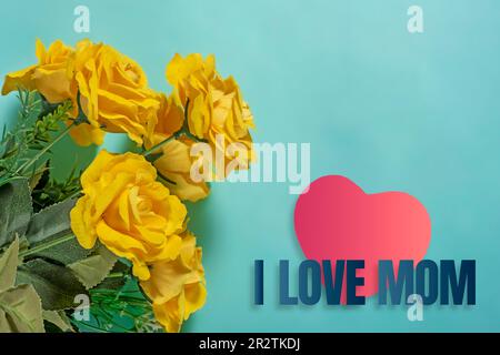 Bouquet di rose gialle con cuore rosso e testo che amo mamma su sfondi blu Foto Stock