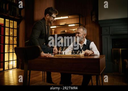 Famiglia intelligente felice che gioca a scacchi che passa il tempo insieme in biblioteca domestica Foto Stock