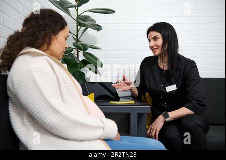 L'operatrice medica consulta la paziente incinta nella sala centrale dell'ospedale di maternità. Assistenza sanitaria. Concetto di gravidanza Foto Stock