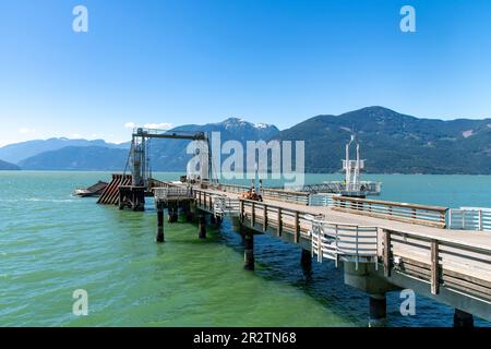 Vista sul molo dei traghetti e sul molo del Porteau Cove Provincial Park vicino a Squamish, British Columbia, Canada, lungo l'Howe Sound con sullo sfondo la montagna innevata Foto Stock