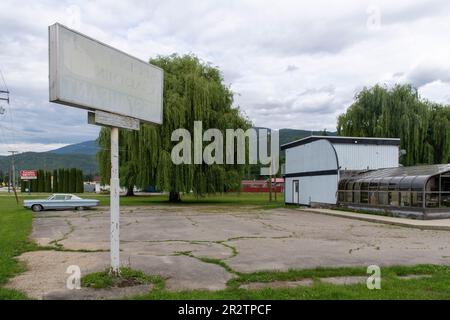 Sicamouse, BC, Canada-Agosto 2022; Vista del terreno con cartello e costruzione di una cena ora chiusa e fatiscente con una classica Chrysler New Y Foto Stock