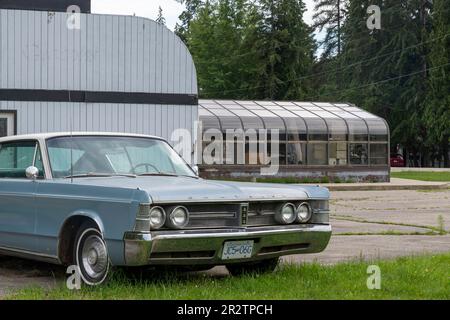 Sicamouse, BC, Canada-Agosto 2022; Vista del terreno e della costruzione di una cena ora chiusa e fatiscente con un classico Chrysler New Yorker parcheggiato in Foto Stock