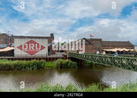 Ulft, Paesi Bassi-Agosto 2022; Vista del ponte sul fiume Oude IJssel verso la DRU Culture Factory, una vecchia fabbrica di ghisa ristrutturata Foto Stock