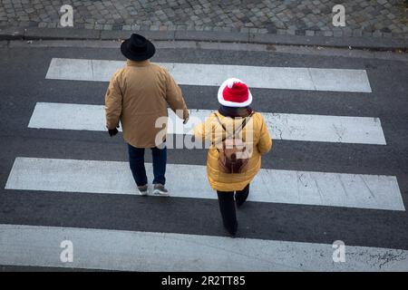 Un uomo e una donna che indossano un cappello di Babbo Natale stanno attraversando un crosswalk a Tunisi Street, Colonia, Germania. ein Mann und eine Frau mit Nikolausmuetze uebe Foto Stock