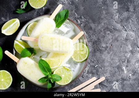 Rinfrescante Lime Popsicles, Lolly di ghiaccio di limonata brasiliana con Lime fresco e menta su sfondo scuro, dessert sano Foto Stock