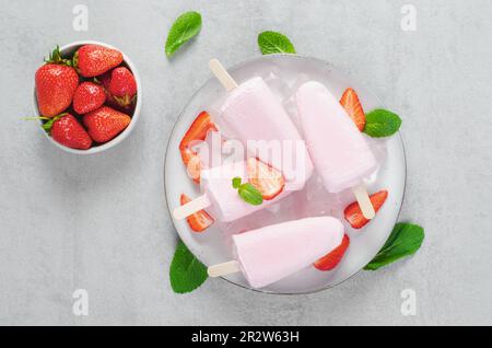 Fresche fragole di fragola, Lolly ghiaccio con fragola fresca e menta su sfondo luminoso, dessert sano Foto Stock