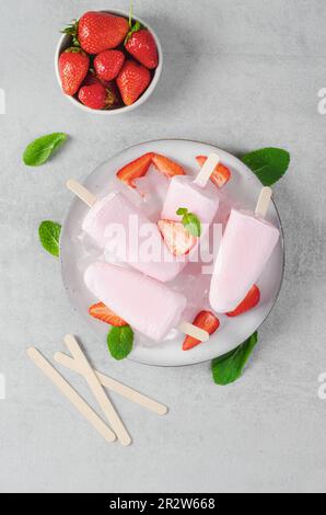 Fresche fragole di fragola, Lolly ghiaccio con fragola fresca e menta su sfondo luminoso, dessert sano Foto Stock