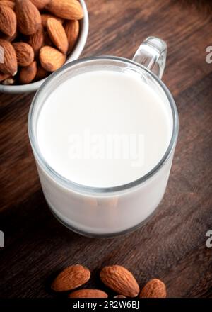 Latte di Mandorla in vetro con le mandorle su sfondo di legno. Foto Stock