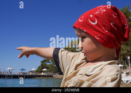 Il bambino mette la mano su qualcosa di interessante nel mare. Vacanze estive in famiglia Foto Stock