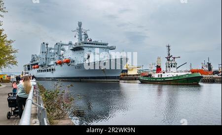 Le persone che osservano l'arrivo della nave navale RFA Forth Victoria trainata da un rimorchiatore nei moli di Leith, Edimburgo, Scozia, Regno Unito Foto Stock