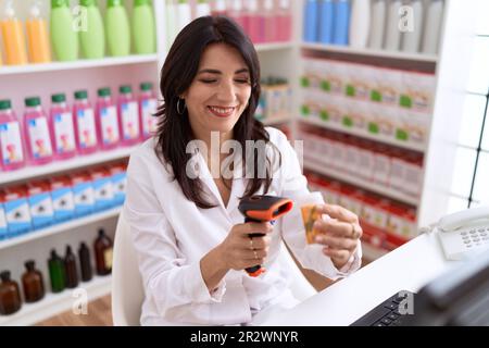 Età media donna ispanica farmacista pillole scansione flacone in farmacia Foto Stock
