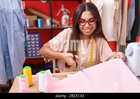 Giovane bella donna araba su misura sorridente sicuro di taglio panno presso atelier Foto Stock