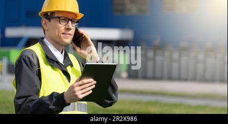 Logistico con telefono e tablet digitale sullo sfondo del centro logistico. Foto di alta qualità Foto Stock