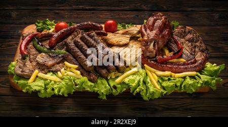 Piatto di legno con piatti misti di carne di maiale collocato su insalate Foto Stock