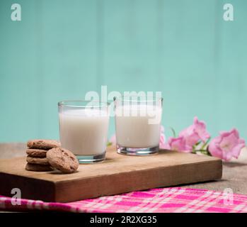 Bicchieri di latte e biscotti sul tagliere. Due bicchieri pieni di latte fresco. Foto Stock