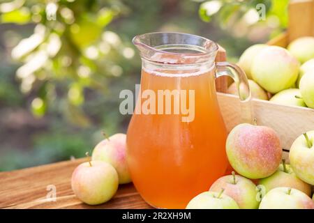 Mele, scatola di mele e brocca di succo di mela fresco su tavola di legno Foto Stock