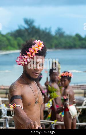 Papua Nuova Guinea, Isole Trobriand, Provincia di Milne Bay, Isola di Kuiawa, anche nota come Kuyau. Giovane uomo in abbigliamento tradizionale alle corse in barca. Foto Stock