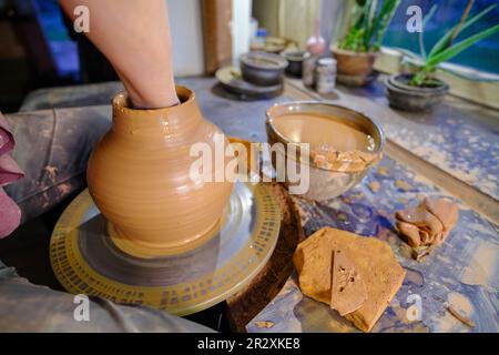 ceramica, laboratorio, arte ceramica concetto - primo piano delle mani dell'uomo che formano un nuovo vaso, le dita dell'uomo che lavorano con la ruota del vasaio e bordo grezzo, fronte Foto Stock