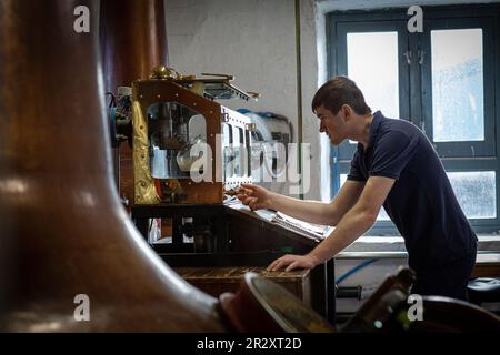 ISLAY, SCOZIA - la distilleria di whisky Kilchoman ancora l'uomo controlla i livelli di alcol nella Spirit Safe. Foto Stock