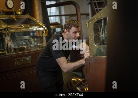 ISLAY, SCOZIA -la distilleria di whisky Bruichladdich ancora l'uomo controlla i livelli di alcol nella Spirit Safe. Foto Stock