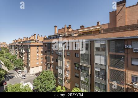 Edifici residenziali urbani in una strada con alberi frondosi Foto Stock