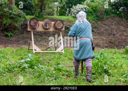 Uomo di epoca medievale che pratica l'ascia gettando su tre bersagli. Foto Stock