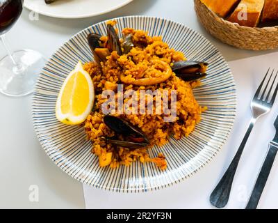 Paella di frutti di mare con cozze, anelli di calamari e limone Foto Stock