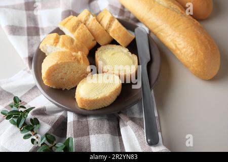 Baguette intere e tagliate con burro fresco in tavola Foto Stock