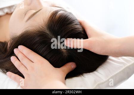 Donna che riceve un massaggio del cuoio capelluto e la mano del praticante Foto Stock